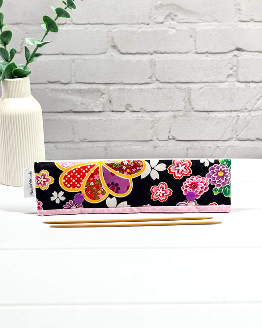 Nadelgarage für 20 cm Nadelspiele mit großen bunten Blumenmotiven im japanischen Stil auf schwarzem Stoff und lila Druckknöpfen. Handgenäht in Bayern von Nadelmikado.