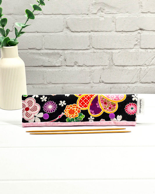 Nadelgarage für 20 cm Nadelspiele mit großen bunten Blumenmotiven im japanischen Stil auf schwarzem Stoff und lila Druckknöpfen. Handgenäht in Bayern von Nadelmikado.