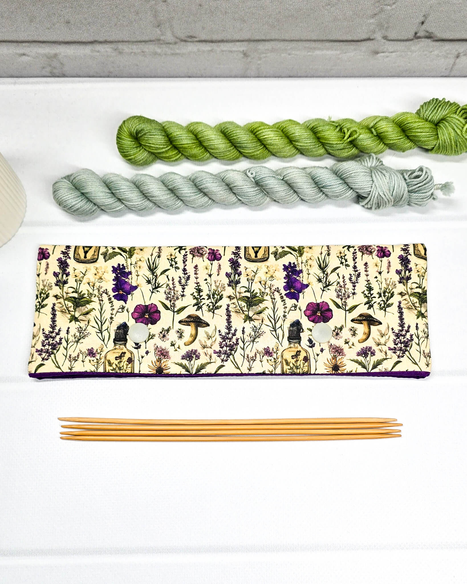 Nadelgarage für 20 cm lange Nadelspiele mit zwei hellen Druckknöpfen und botanischem Kräuterküche-Muster auf beigem Grund. Handgenäht in Bayern von Nadelmikado.