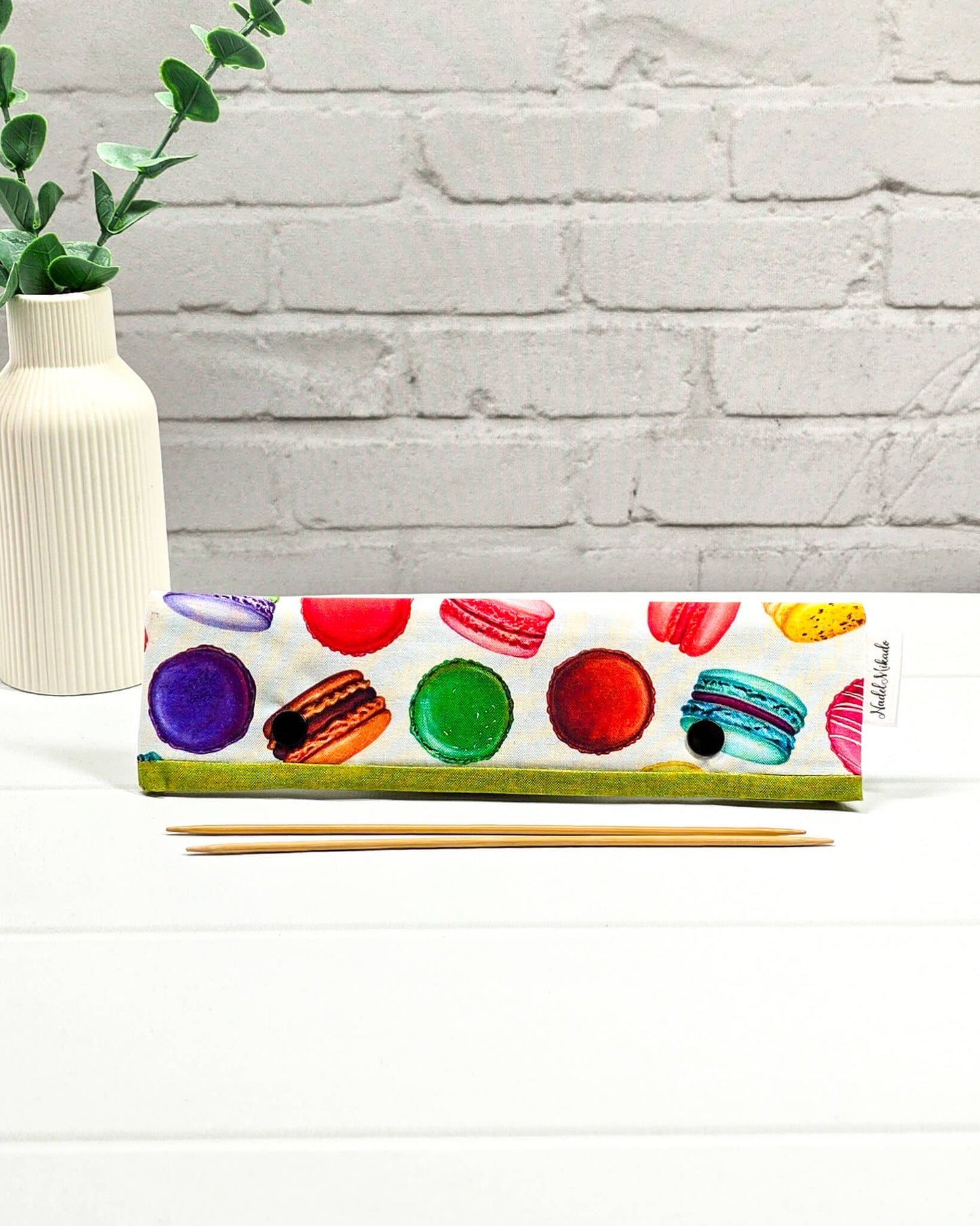 Nadelgarage für 20 cm Nadelspiele mit bunten Macarons in Pink, Grün und Gelb auf hellem Stoff mit grüner Bordüre und schwarzen Druckknöpfen. Handgenäht in Bayern von Nadelmikado
