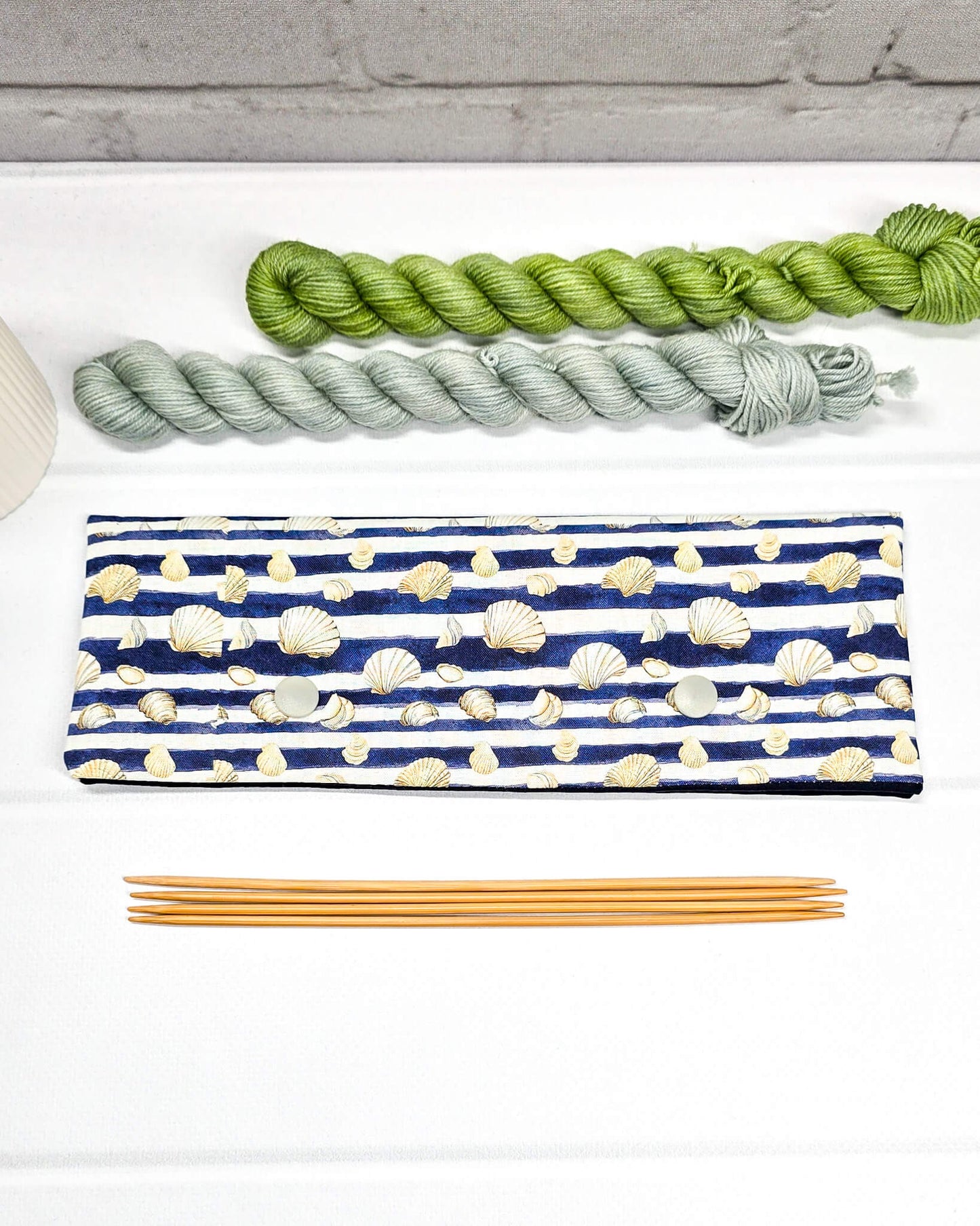Nadelgarage für 20cm Nadelspiele aus blau-weiß gestreiftem Stoff mit Muschelmotiven und zwei hellgrauen Druckknöpfen. Handgenäht in Bayern von Nadelmikado. 