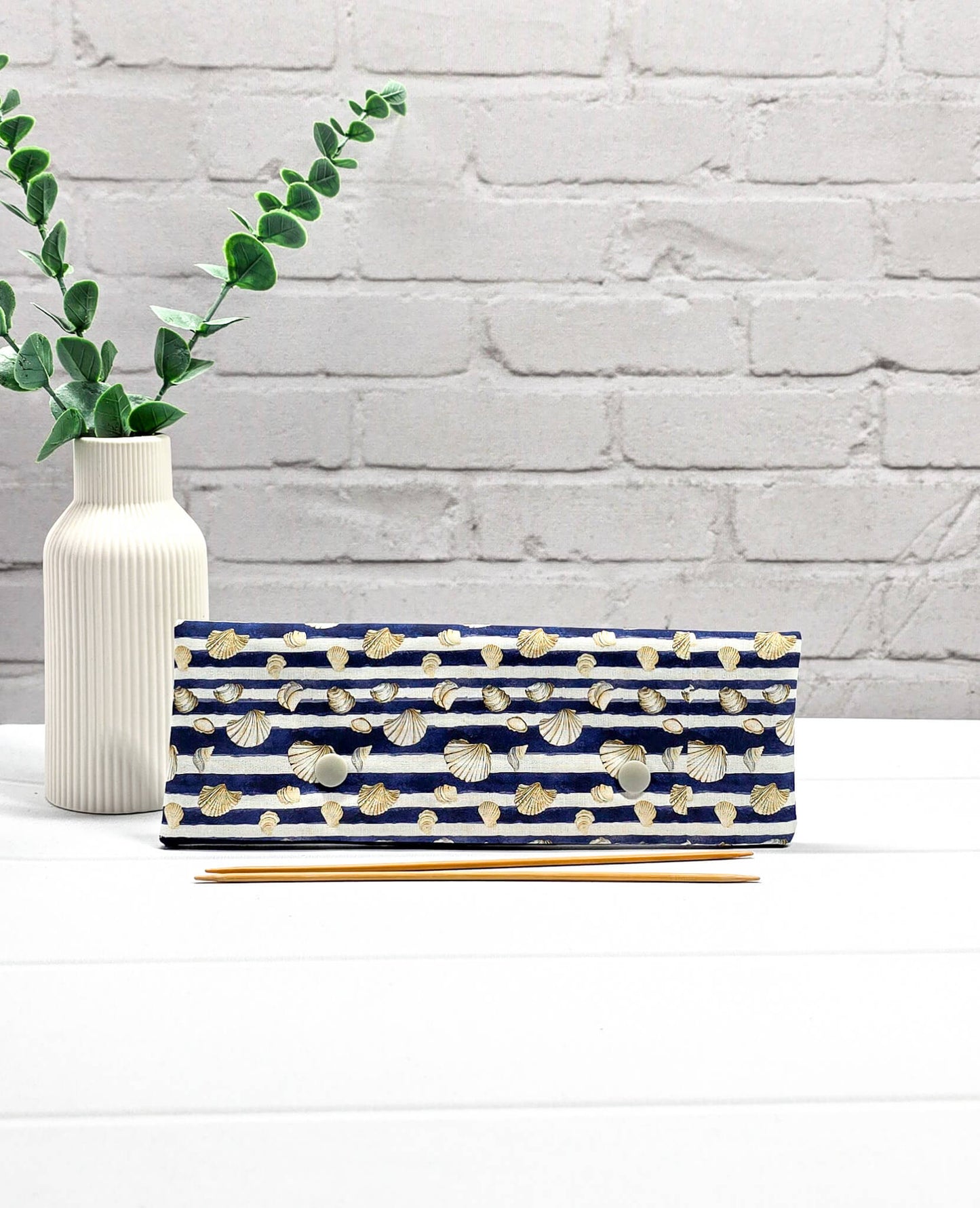 Nadelgarage für 20cm Nadelspiele aus blau-weiß gestreiftem Stoff mit Muschelmotiven und zwei hellgrauen Druckknöpfen. Handgenäht in Bayern von Nadelmikado. 