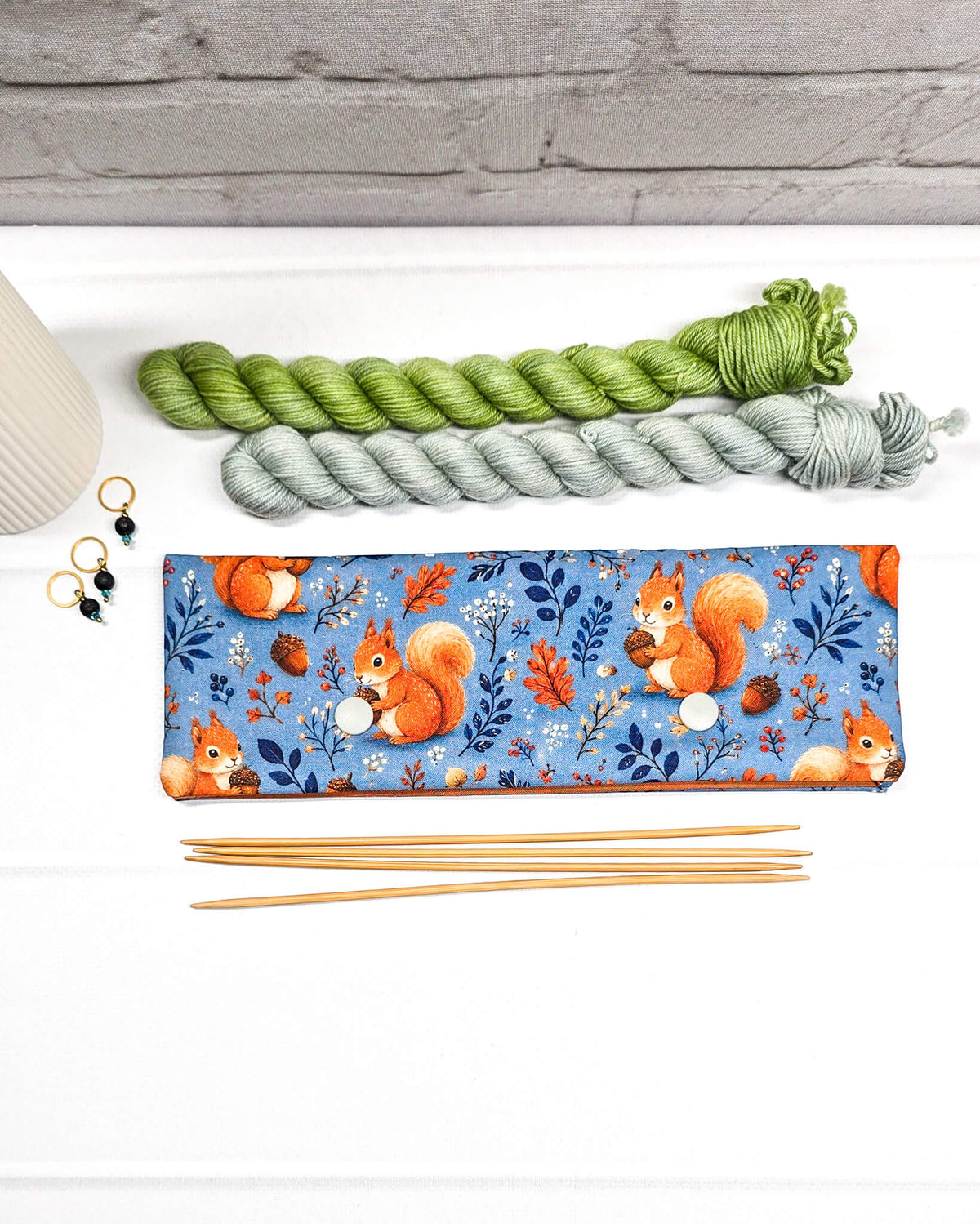 Nadelgarage für 20 cm Nadelspiele aus blauem Baumwollstoff mit orangefarbenen Eichhörnchen, Eicheln und zwei Druckknöpfen. Schützt Stricknadeln und Maschen. Handgenäht in Bayern von Nadelmikado.