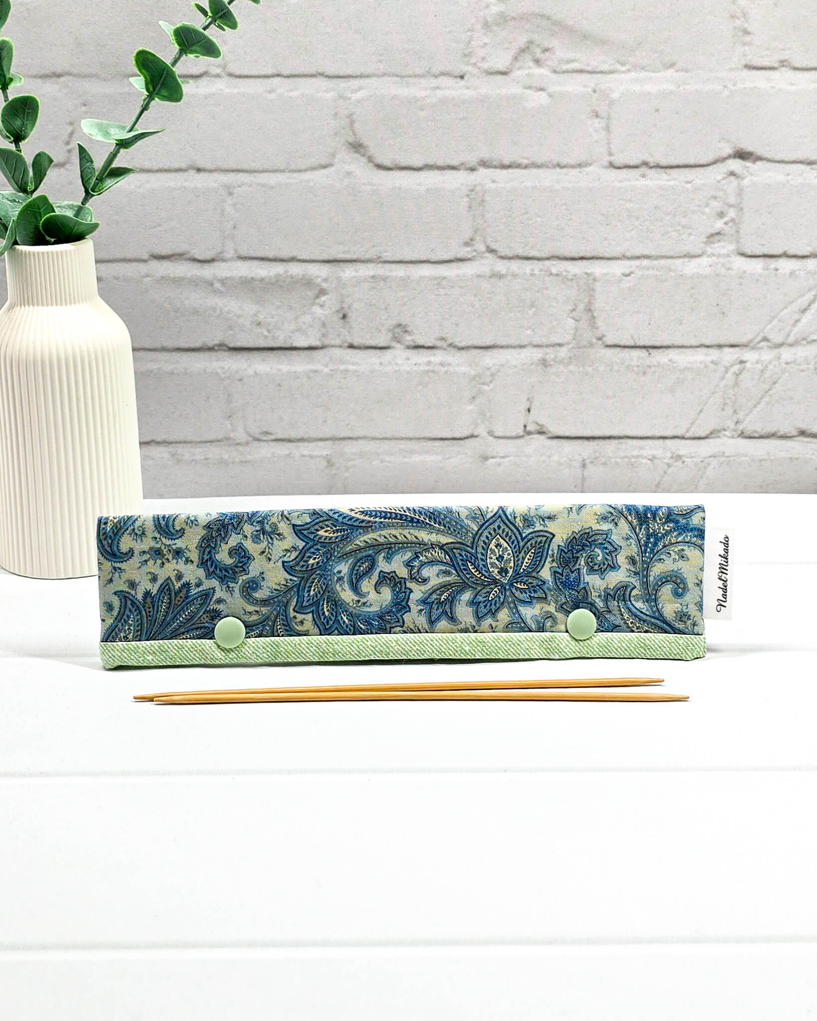 Nadelgarage für 20 cm Nadelspiele mit blauem Paisley-Muster, hellgrüner Bordüre und zwei grünen Druckknöpfen. Handgenäht in Bayern von Nadelmikado