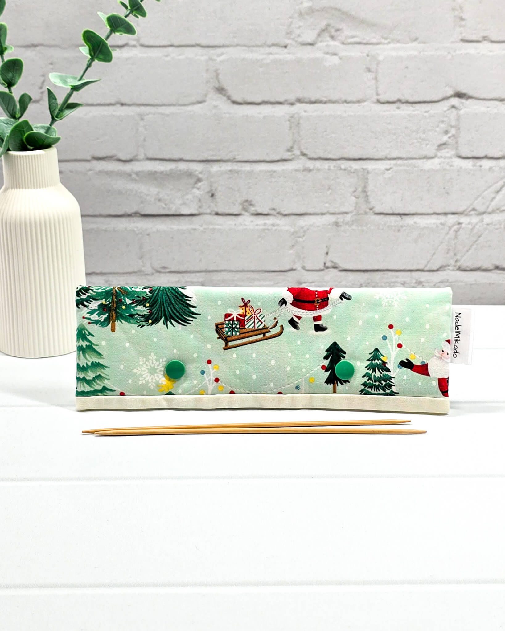 Nadelgarage für 20 cm Nadelspiele mit Motiven vom Weihnachtsmann, Schlitten und Tannenbäumen auf mintgrünem Stoff mit grünen Druckknöpfen. Handgenäht in Bayern von Nadelmikado