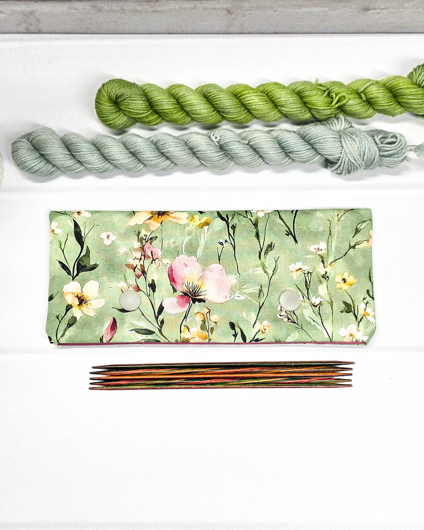 Nadelgarage für 15cm Nadelspiele mit buntem Wildblumenmotiv auf salbeigrünem Grund und zwei hellgrauen Druckknöpfen. Handgenäht in Bayern von Nadelmikado.