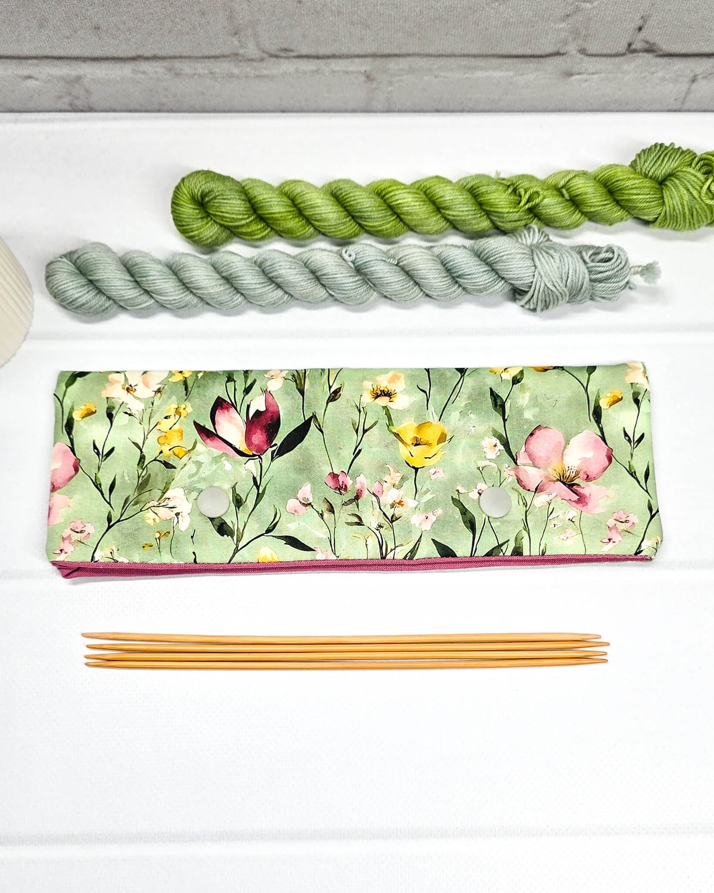 Lange Nadelgarage für 20cm Nadelspiele mit buntem Wildblumenmotiv auf salbeigrünem Grund und zwei hellgrauen Druckknöpfen. Handgenäht in Bayern von Nadelmikado.