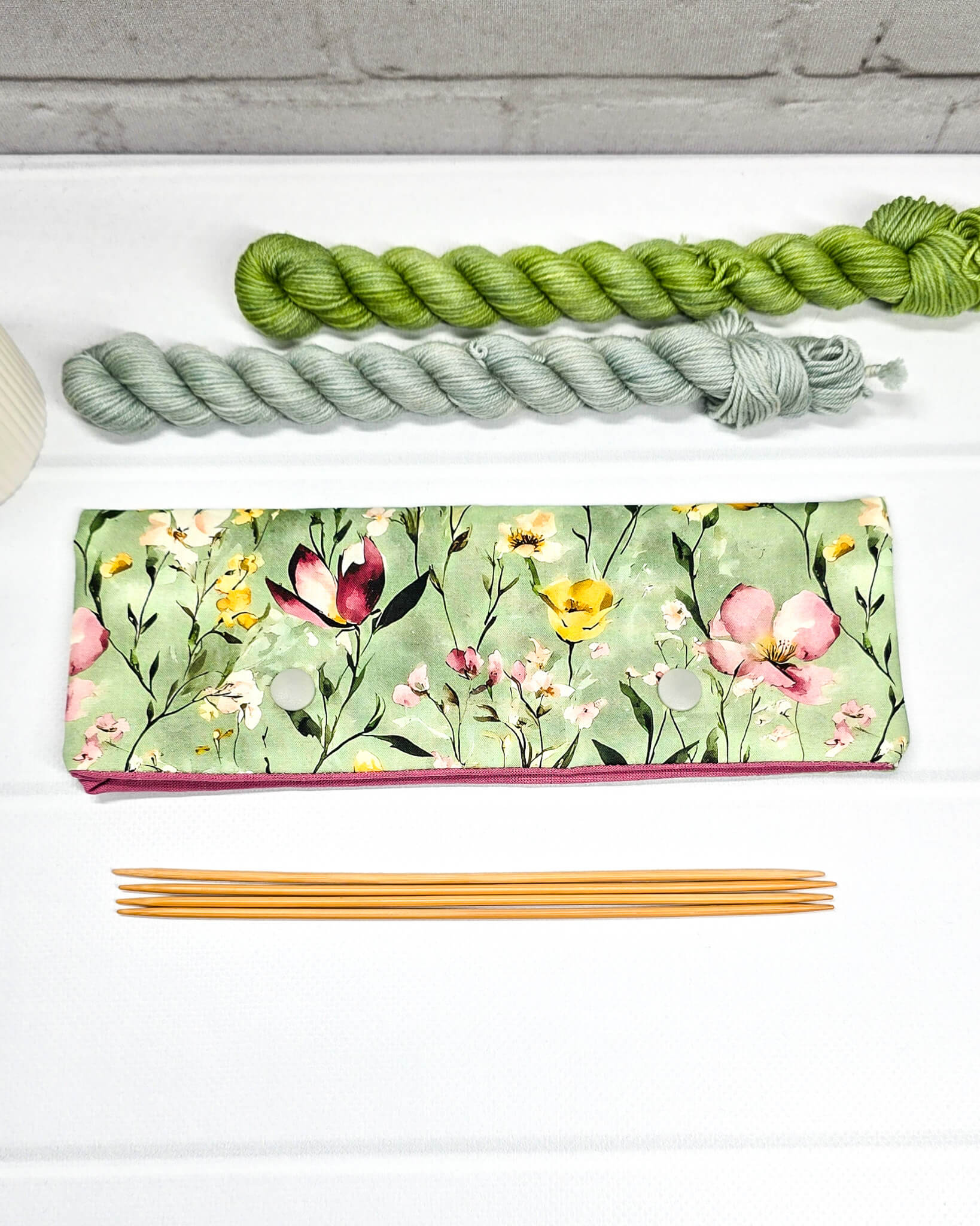 Lange Nadelgarage für 20cm Nadelspiele mit buntem Wildblumenmotiv auf salbeigrünem Grund und zwei hellgrauen Druckknöpfen. Handgenäht in Bayern von Nadelmikado.