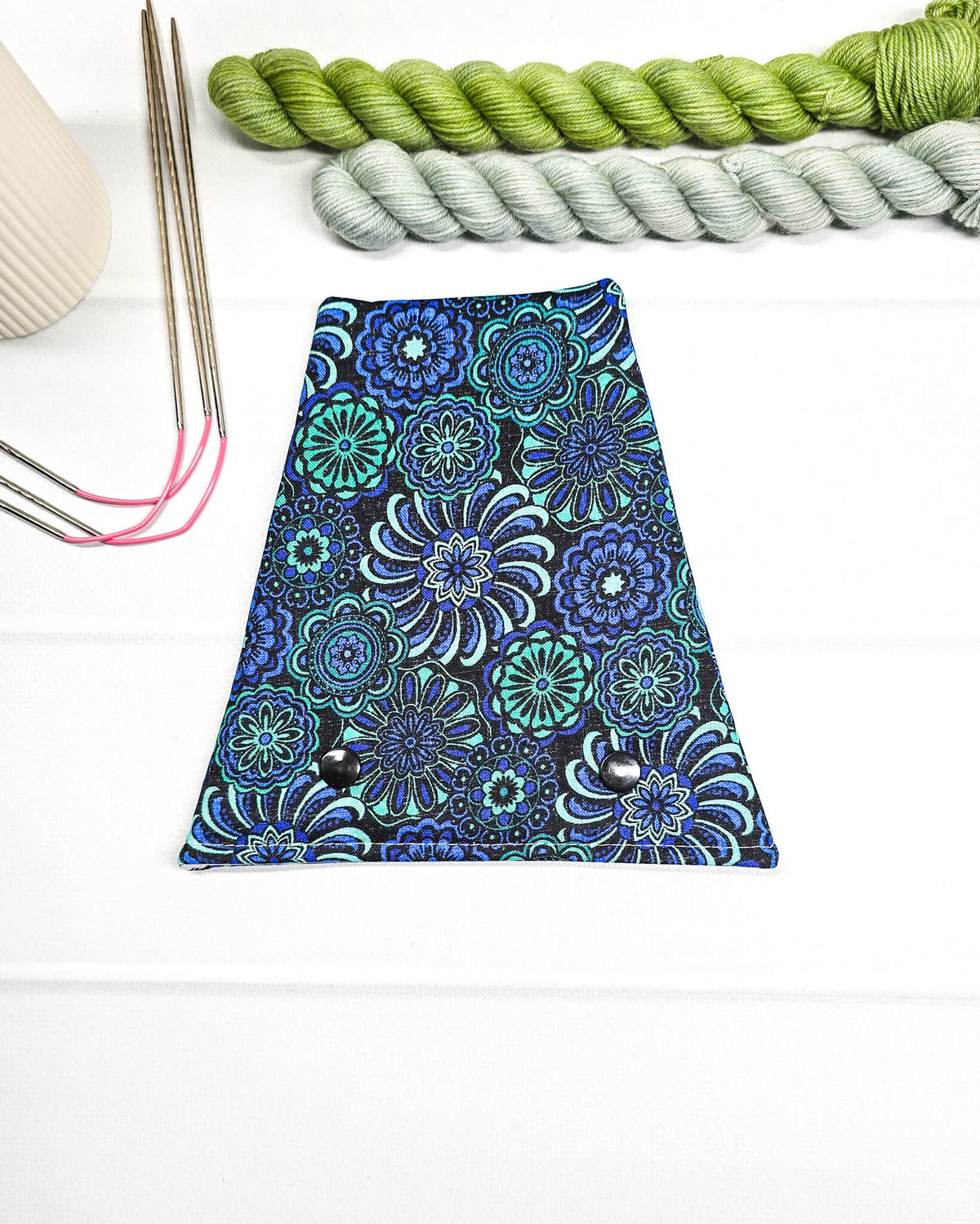 Nadelgarage für Trio-Stricknadeln mit floralen Ornamenten in Blau, Türkis und Schwarz sowie zwei schwarzen Druckknöpfen. Handgenäht in Bayern von Nadelmikado.