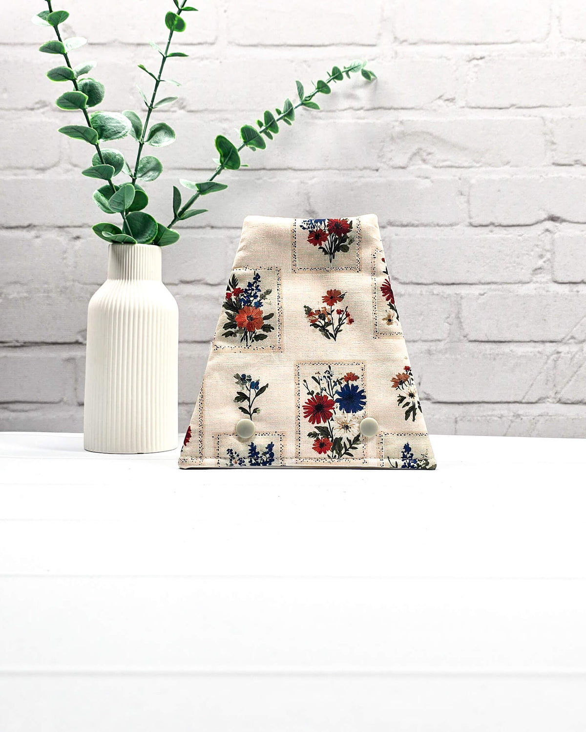 Nadelgarage für Trio-Stricknadeln aus hellem Stoff mit kleinen floralen Motiven in Rot, Blau und Orange sowie zwei hellen Druckknöpfen. Handgenäht in Bayern von Nadelmikado.