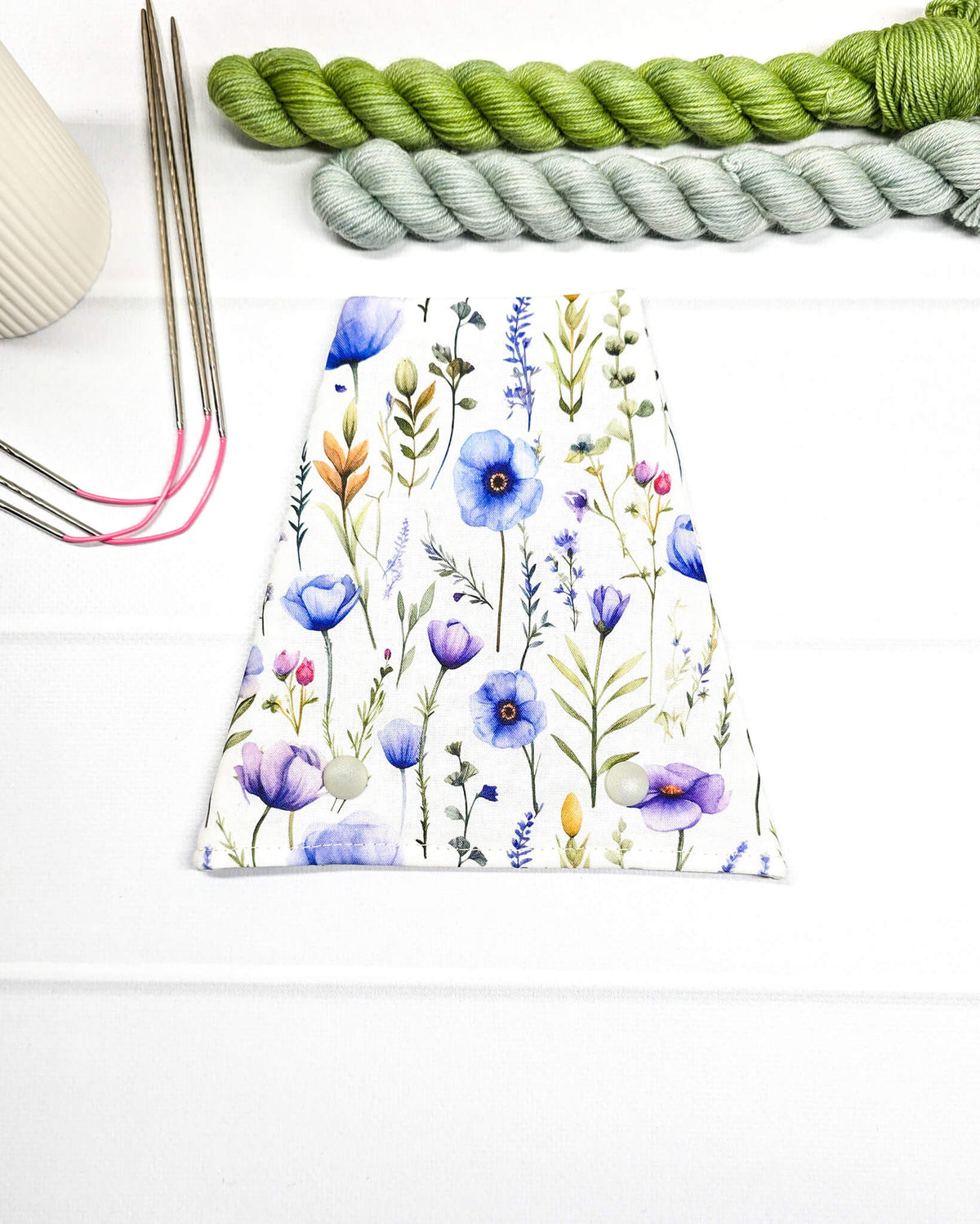Nadelgarage für Trio-Stricknadeln aus weißem Stoff mit zarten Wildblumen in Blau, Lila und Grün sowie zwei hellen Druckknöpfen. Handgenäht in Bayern von Nadelmikado.