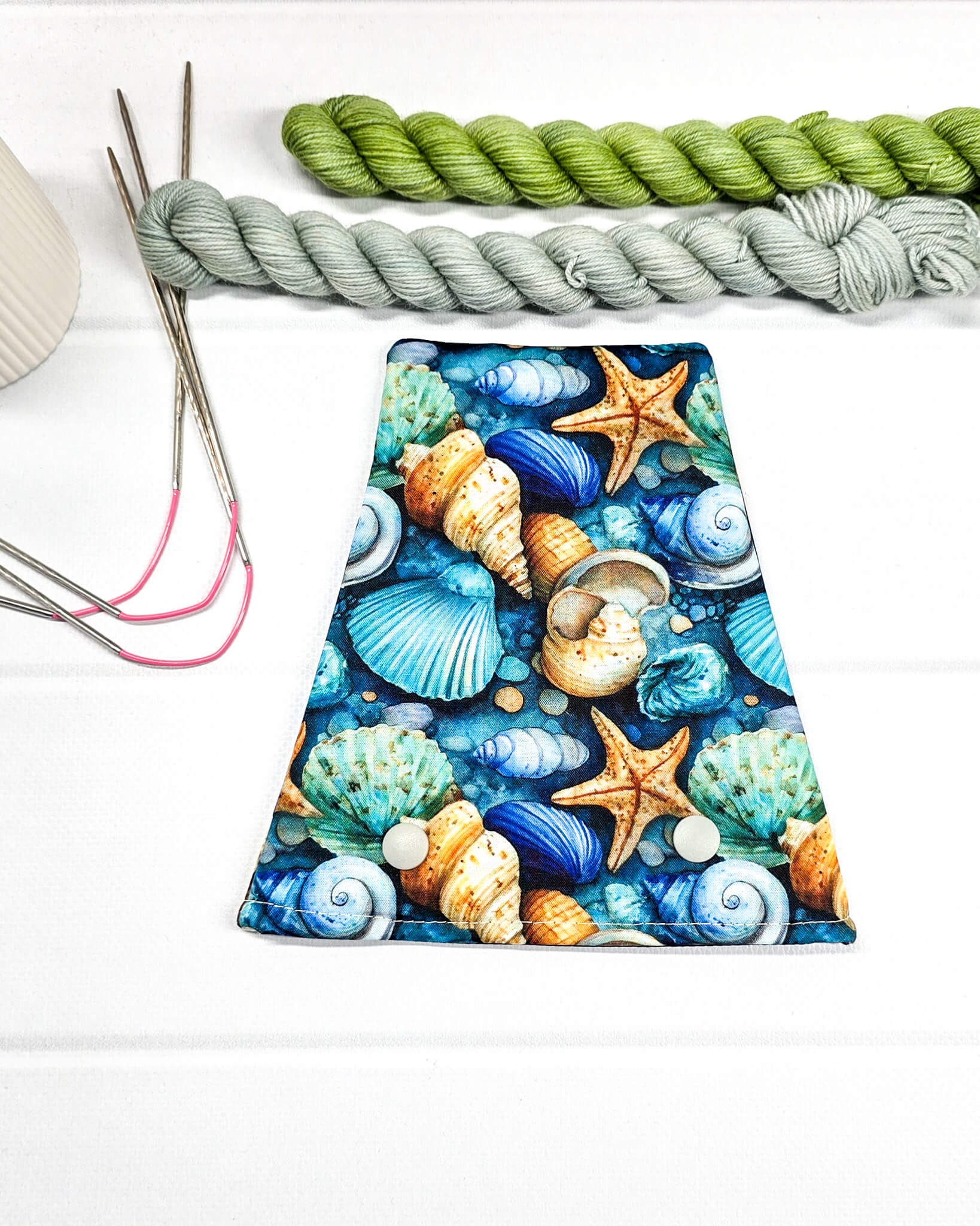 Nadelgarage für Trios aus buntem Stoff mit detaillierten Seesternen und Muscheln in Blau und Türkis sowie zwei hellen Druckknöpfen. Handgenäht in Bayern von Nadelmikado. 