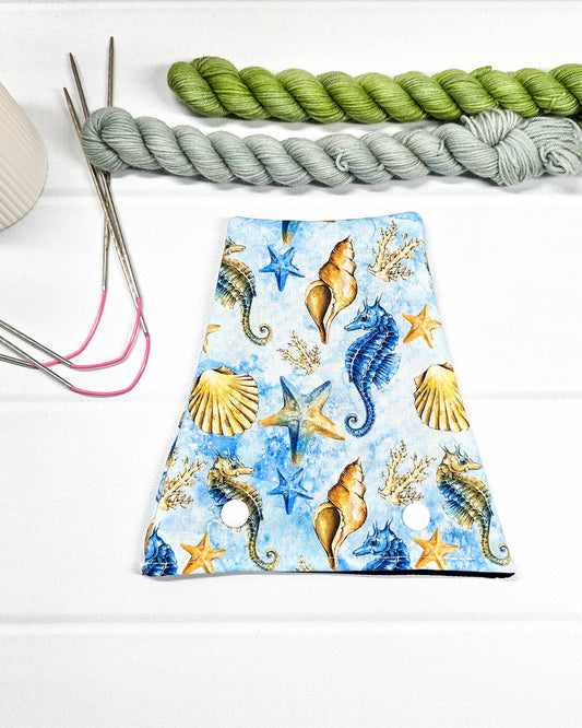 Nadelgarage für Trios aus hellblauem Stoff mit Seepferdchen, Seesternen, Muschelmotiven und zwei weißen Druckknöpfen. Handgenäht in Bayern von Nadelmikado. 