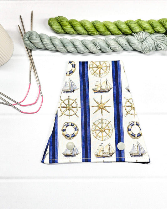 Nadelgarage für Trios aus cremeweißem Stoff mit blauen Streifen, goldenen Steuerrädern, Segelschiffen und zwei hellen Druckknöpfen. Handgenäht in Bayern von Nadelmikado. 