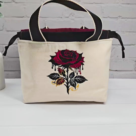 Projekttasche Alva S aus hellem Canvas mit gestickter Gothic Rose, schwarzen Henkeln und Kordelzug. Handgenäht in Bayern von Nadelmikado.