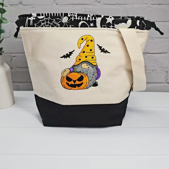 Projekttasche Tuva M aus hellem Canvas mit gesticktem Halloween Gnom, Kürbis und schwarzem Kordelzugkragen. Handgenäht in Bayern von Nadelmikado.