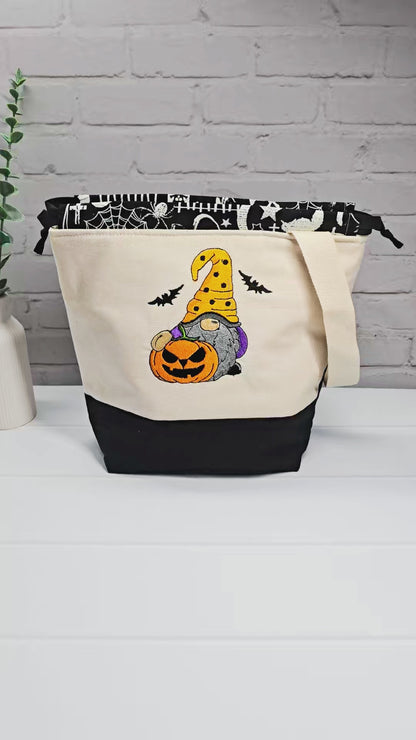 Projekttasche Tuva M aus hellem Canvas mit gesticktem Halloween Gnom, Kürbis und schwarzem Kordelzugkragen. Handgenäht in Bayern von Nadelmikado.