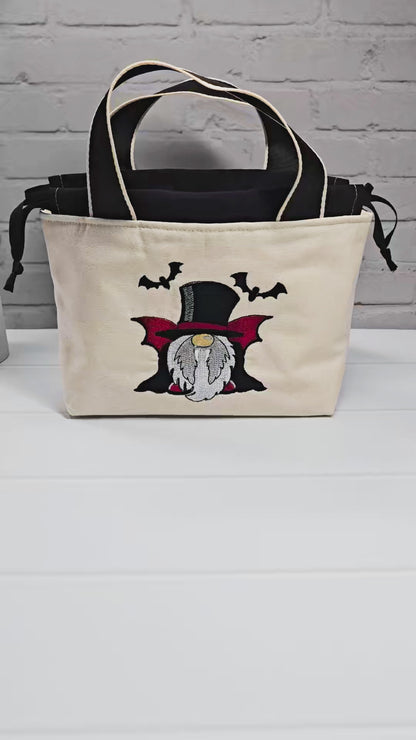 Projekttasche Alva S aus hellem Canvas mit gesticktem Vampir-Wichtel und Fledermäusen, Henkeln und schwarzem Kordelzug. Handgenäht in Bayern von Nadelmikado.