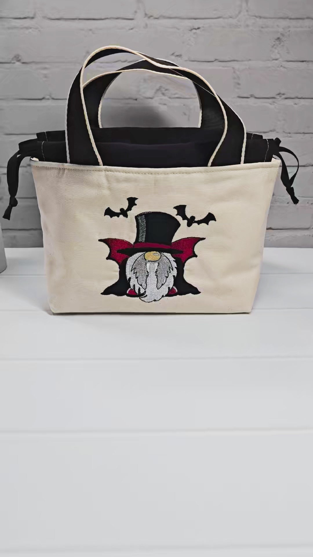 Projekttasche Alva S aus hellem Canvas mit gesticktem Vampir-Wichtel und Fledermäusen, Henkeln und schwarzem Kordelzug. Handgenäht in Bayern von Nadelmikado.