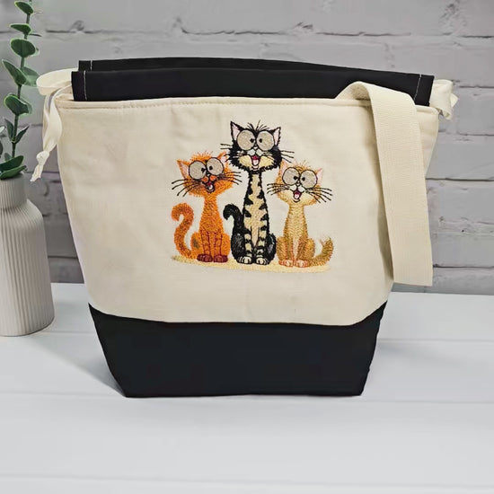 Projekttasche Tuva M aus hellem Canvas und Schwarz mit gesticktem lustigen Katzen Trio und Kordelzugverschluss. Handgenäht in Bayern von Nadelmikado.