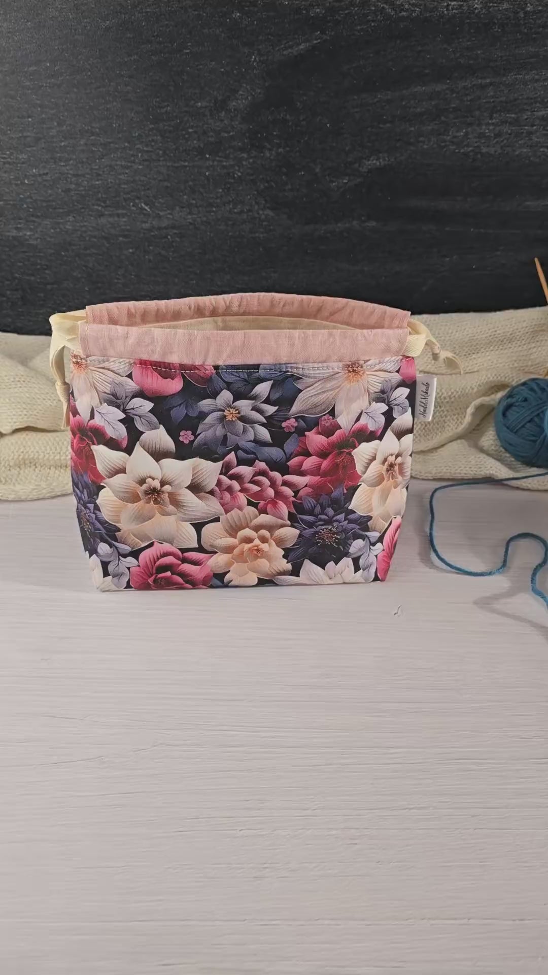 Florale Stricktasche auf weißem Hintergrund, ideal für organisierte und stilvolle Handarbeitsprojekte.