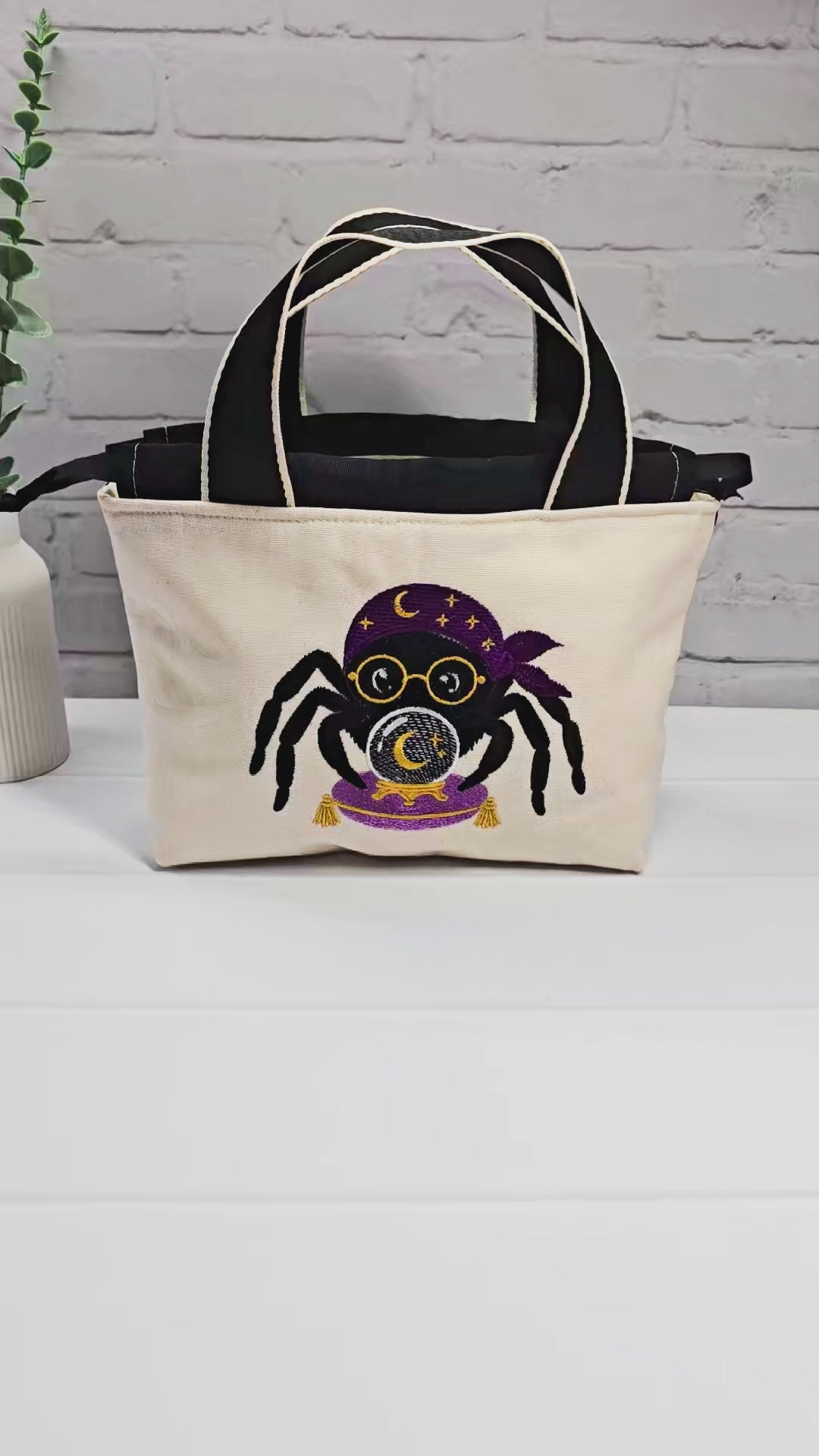 Projekttasche Alva S aus hellem Canvas mit gestickter Wahrsager Spinne und Kristallkugel, Henkeln und schwarzem Kordelzugkragen. Handgenäht in Bayern von Nadelmikado.