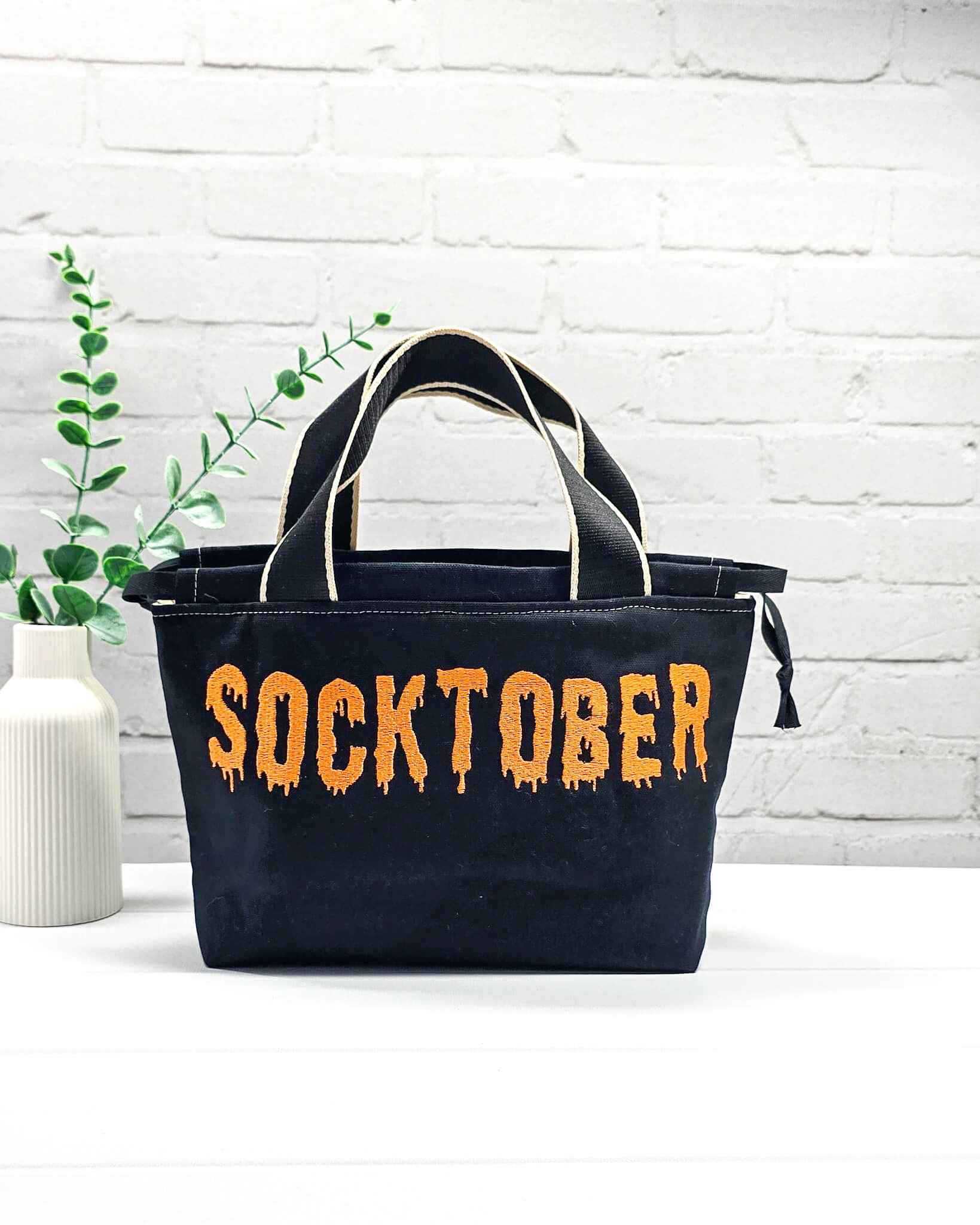 Bestickter Projektbeutel Alva S aus schwarzem Canvas mit orangefarbenem Socktober-Schriftzug, handgenäht in Bayern von NadelMikado