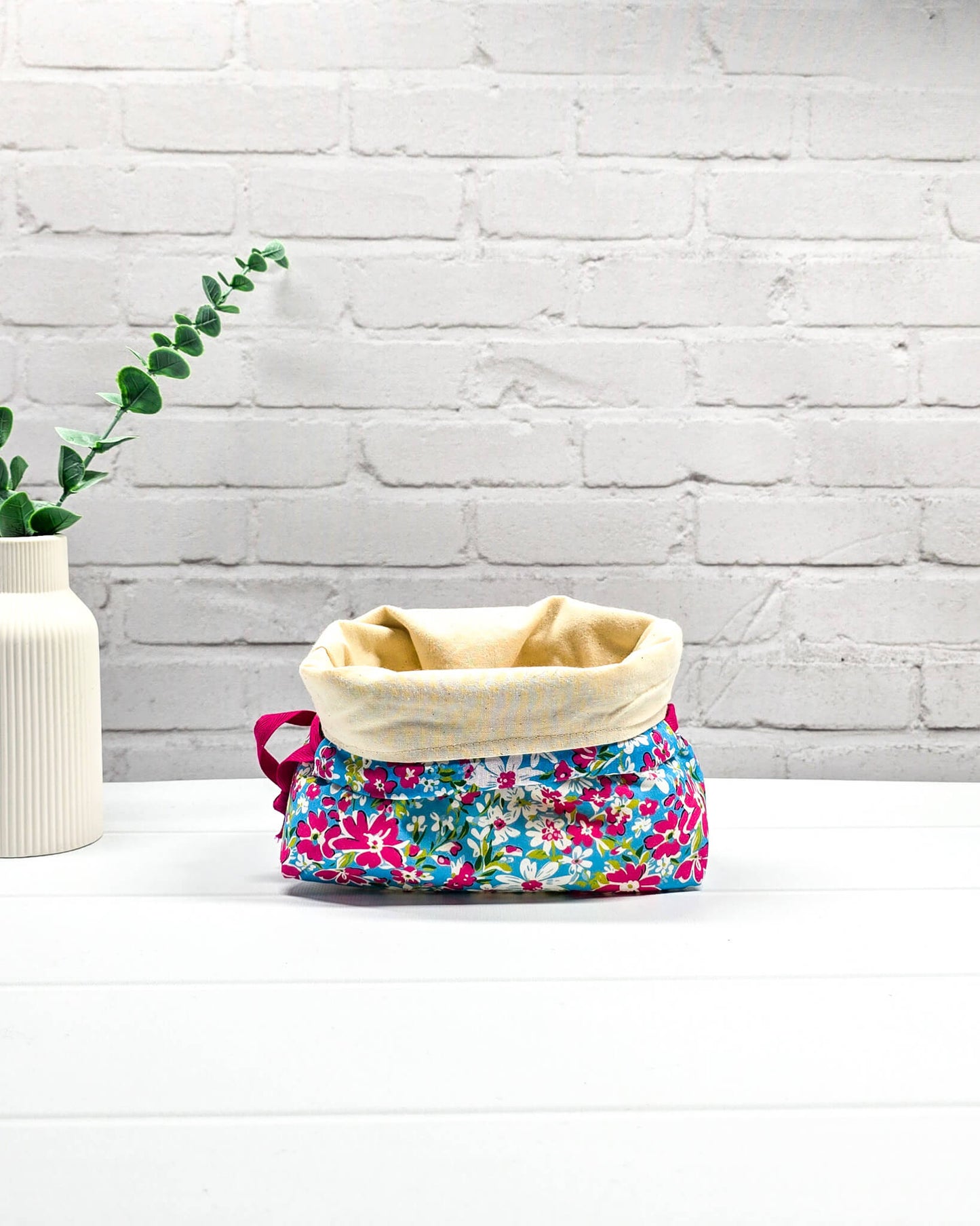 Projektbeutel Lyra mit pinken und weißen Blumen auf türkisfarbenem Grund und mit pinkem Kordelzug. Handgenäht in Bayern von Nadelmikado 