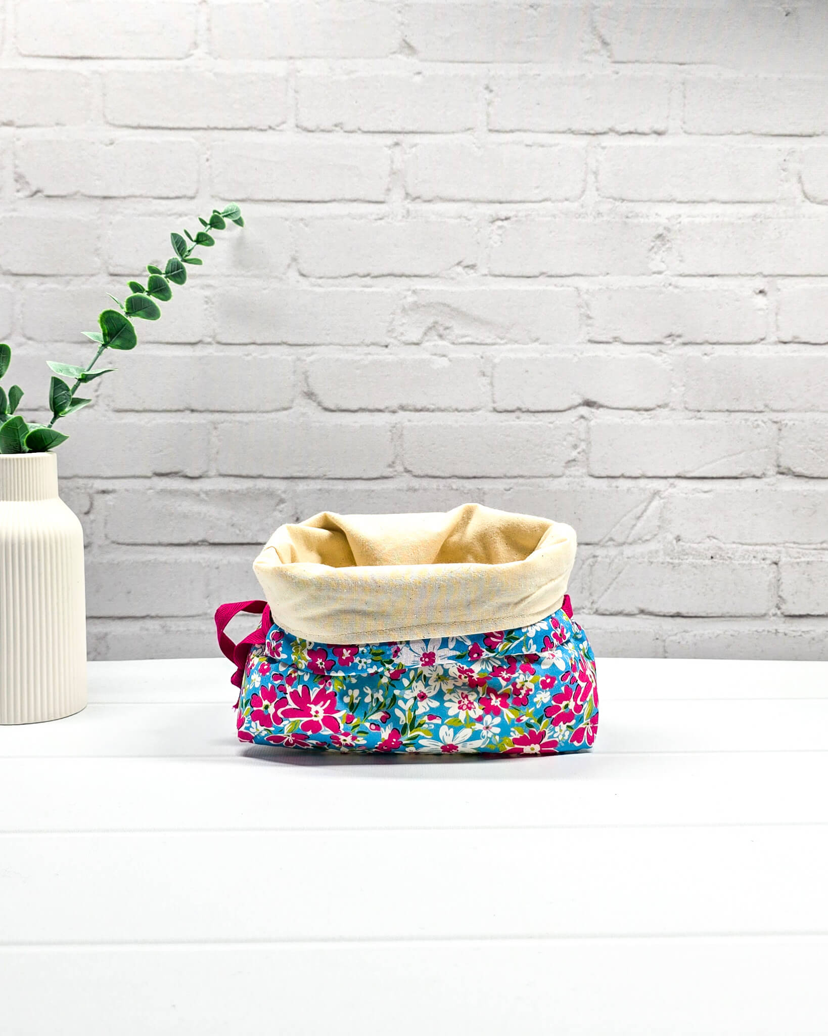 Projektbeutel Lyra mit pinken und weißen Blumen auf türkisfarbenem Grund und mit pinkem Kordelzug. Handgenäht in Bayern von Nadelmikado 