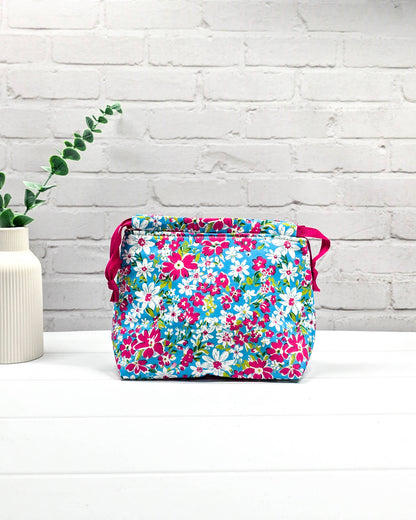 Projektbeutel Lyra mit pinken und weißen Blumen auf türkisfarbenem Grund und mit pinkem Kordelzug. Handgenäht in Bayern von Nadelmikado 