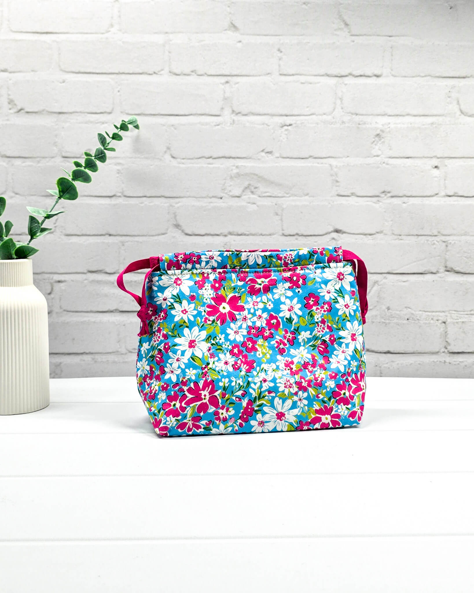 Projektbeutel Lyra mit pinken und weißen Blumen auf türkisfarbenem Grund und mit pinkem Kordelzug. Handgenäht in Bayern von Nadelmikado 