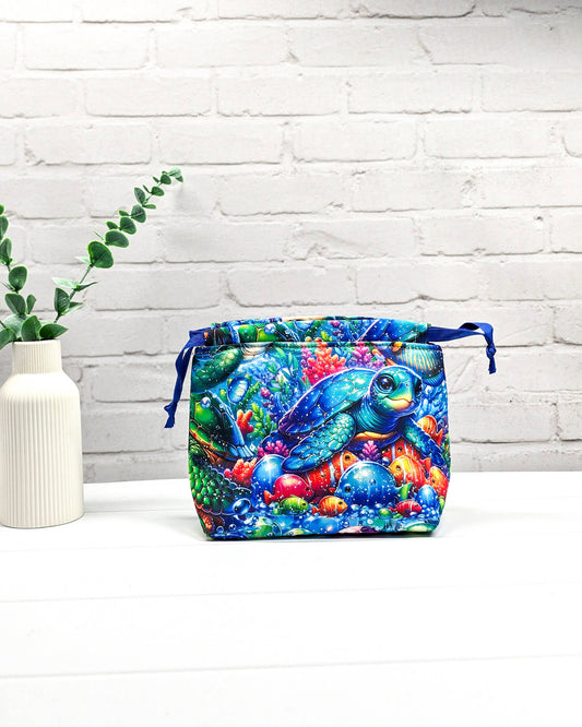 Projektbeutel Lyra mit einem bunten Motiv aus Meeresschildkröten und Fischen unter Wasser sowie blauem Kordelzug. Handgenäht in Bayern von Nadelmikado. 