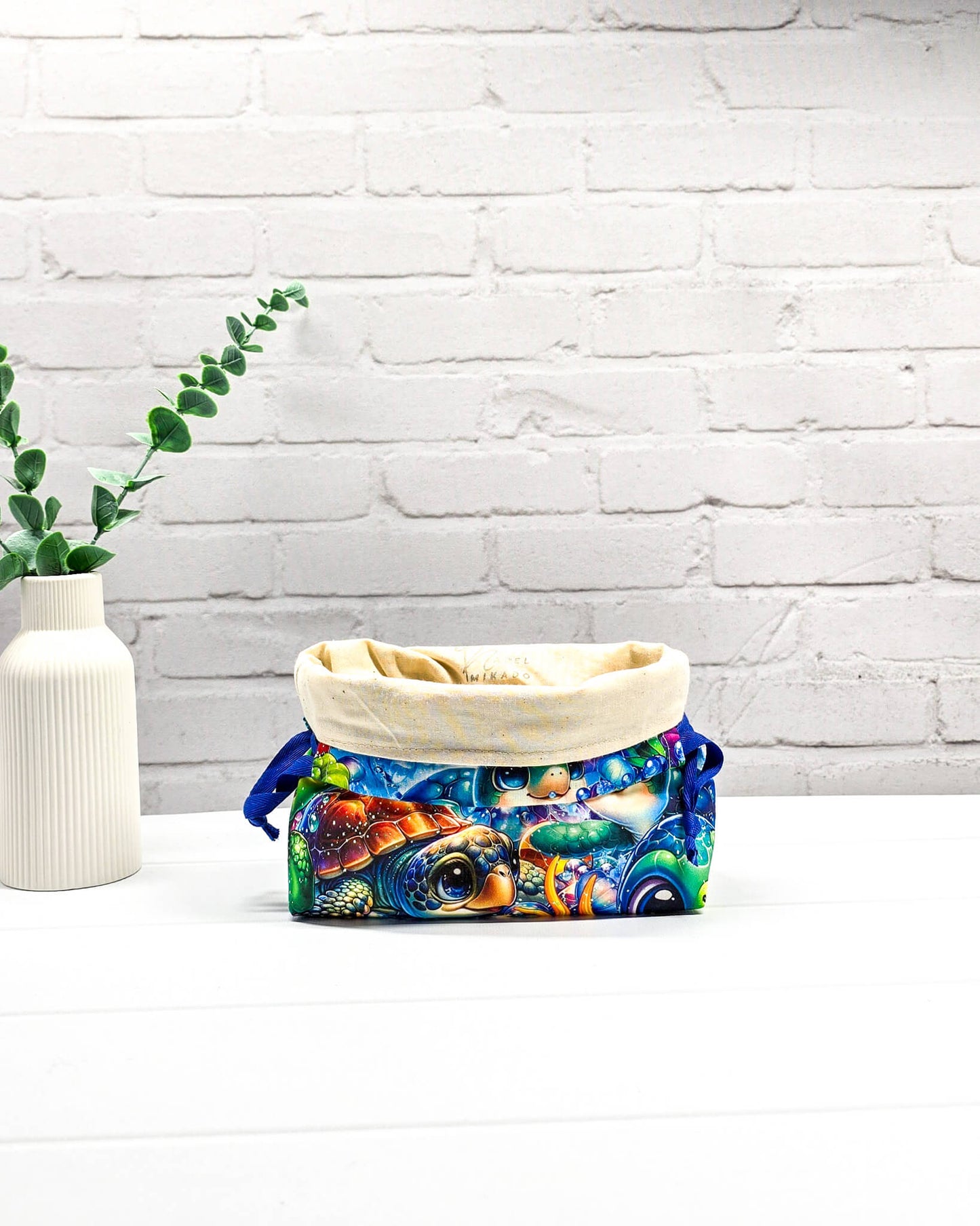 Projektbeutel Lyra mit einem bunten Motiv aus Meeresschildkröten und Fischen unter Wasser sowie blauem Kordelzug. Handgenäht in Bayern von Nadelmikado. 