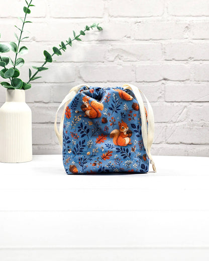 Kleiner Projektbeutel Tindra mit Tunnelzug aus blauem Baumwollstoff mit orangefarbenen Eichhörnchen, Eicheln und Blättern für Strickprojekte bis 50 g Wolle. Handgenäht in Bayern von Nadelmikado.