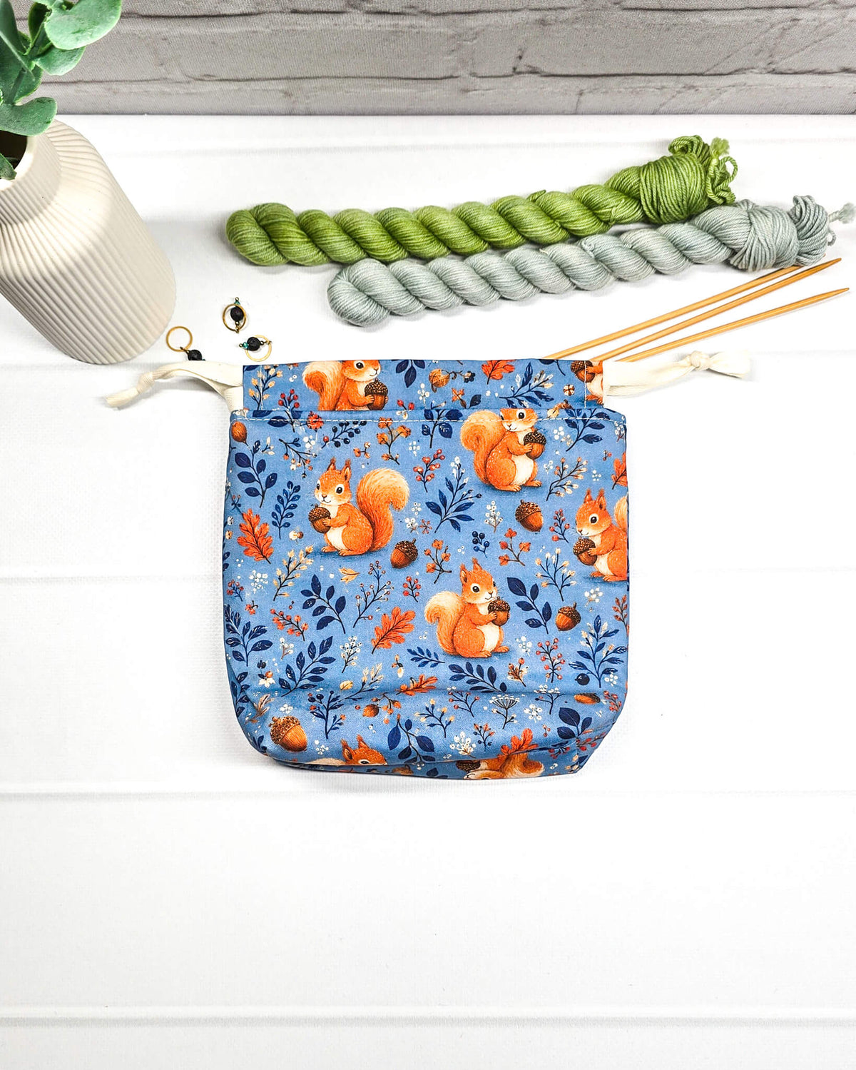 Kleiner Projektbeutel Tindra mit Tunnelzug aus blauem Baumwollstoff mit orangefarbenen Eichhörnchen, Eicheln und Blättern für Strickprojekte bis 50 g Wolle. Handgenäht in Bayern von Nadelmikado.