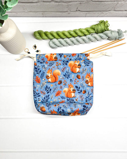 Kleiner Projektbeutel Tindra mit Tunnelzug aus blauem Baumwollstoff mit orangefarbenen Eichhörnchen, Eicheln und Blättern für Strickprojekte bis 50 g Wolle. Handgenäht in Bayern von Nadelmikado.