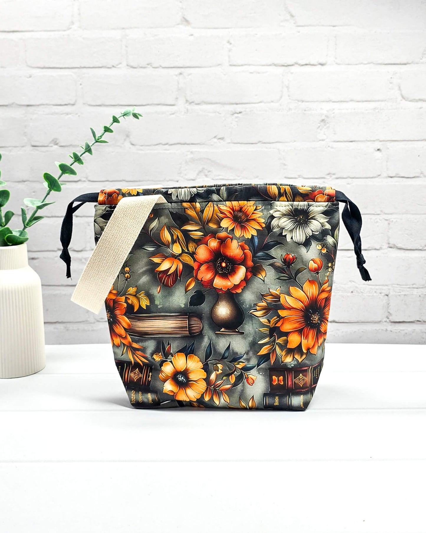 Projekttasche Tuva S mit Vintage-Büchern und floralen Motiven auf dunklem Stoff für Socken- oder Mützenprojekte - handgenäht in Bayern von Nadelmikado