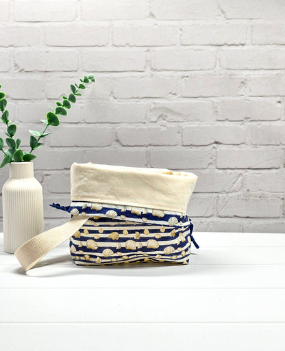 Projektbeutel Tuva S aus blau-weiß quergestreiftem Stoff mit kleinen Muschelmotiven, einer hellen Gurtband-Schlaufe und dunkelblauem Kordelzug. Handgenäht in Bayern von Nadelmikado. 