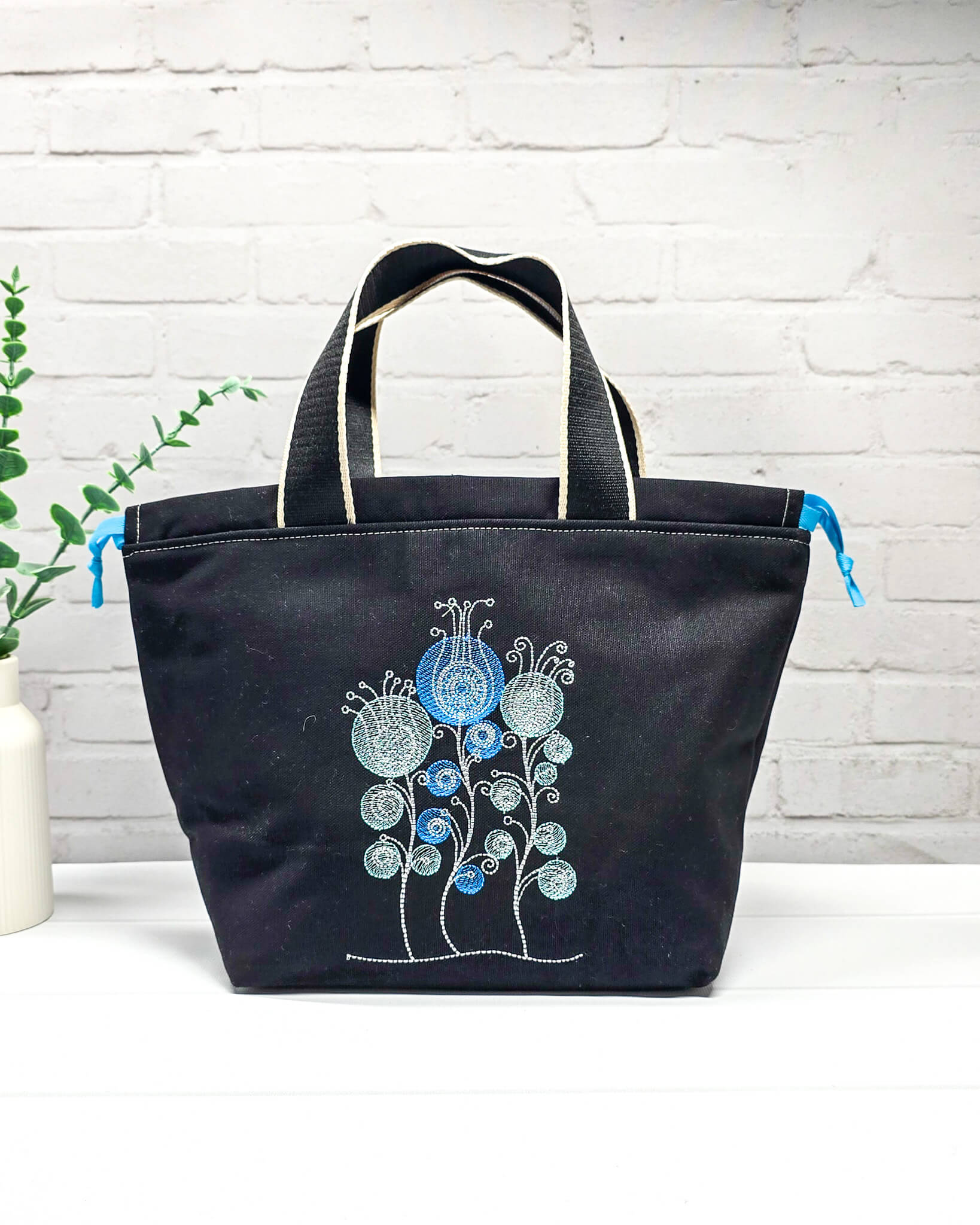 Projekttasche Alva M mit gestickten Blüten auf dunklem Canvas, handgenäht in Bayern von Nadelmikado