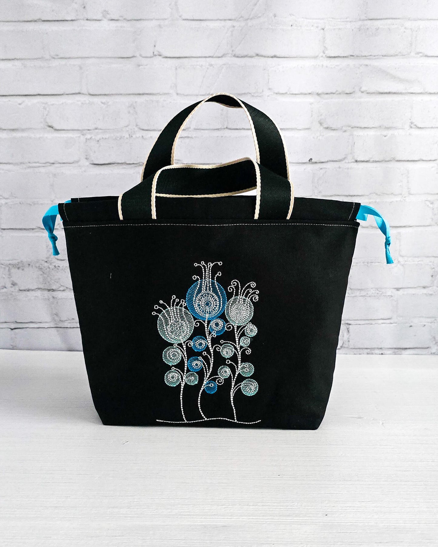 Projekttasche Alva M mit gestickten Blüten auf dunklem Canvas, handgenäht in Bayern von Nadelmikado