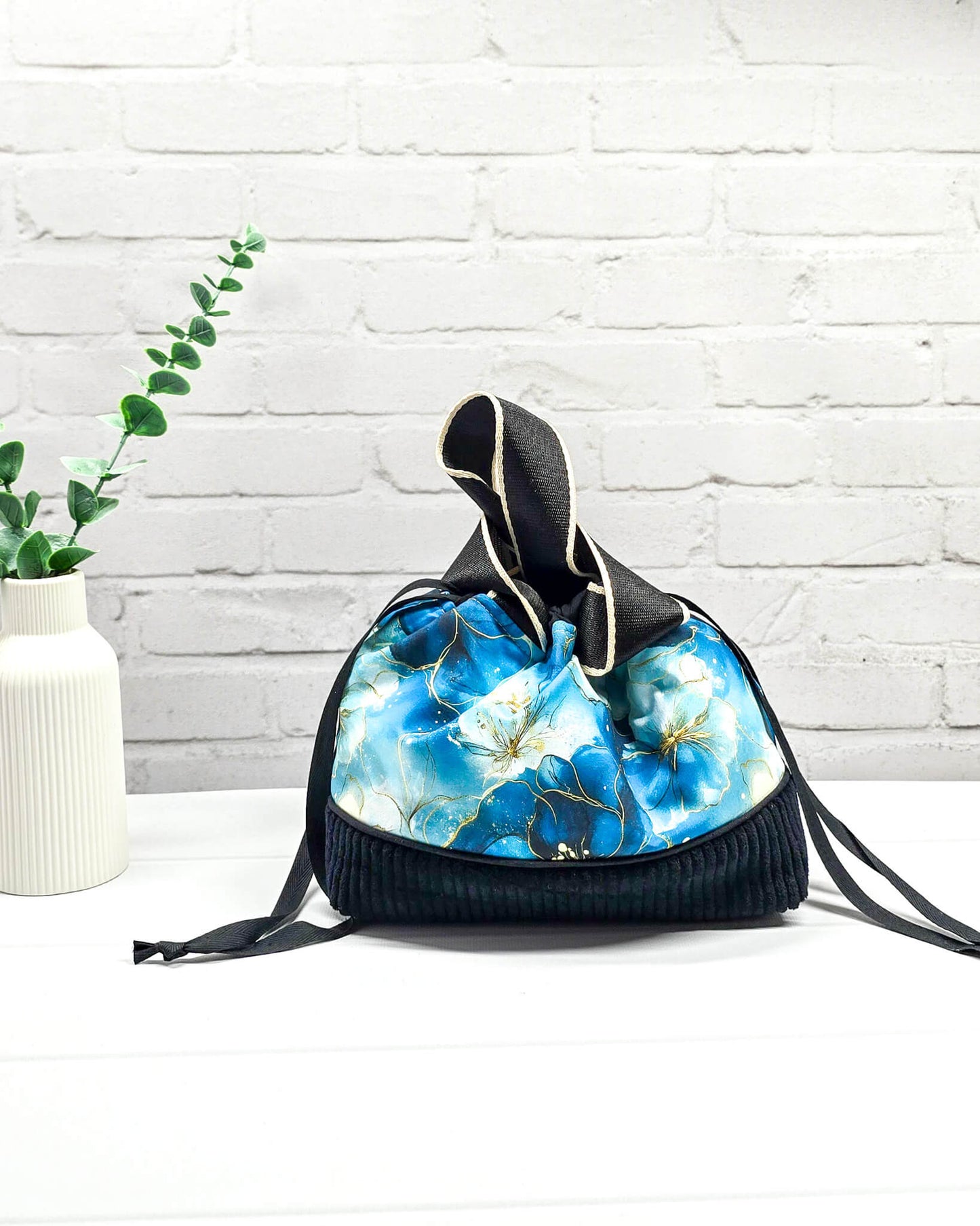 Handgemachte Projekttasche Alva in Größe S mit zwei Tragegriffen, blauen Aquarellblüten und einem Taschenboden aus schwarzem Breitcord. Handgenäht in Bayern von Nadelmikado. 