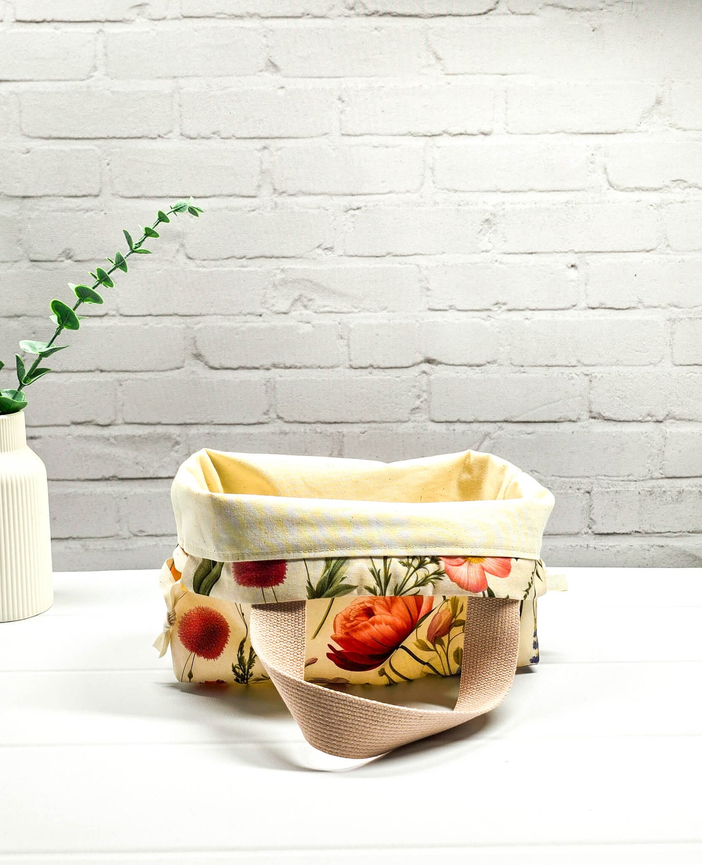 Handgenähte Projekttasche Alva S von Nadelmikado mit feinen botanischen Blumen-Illustrationen auf hellem Stoff, beige Tragehenkel.