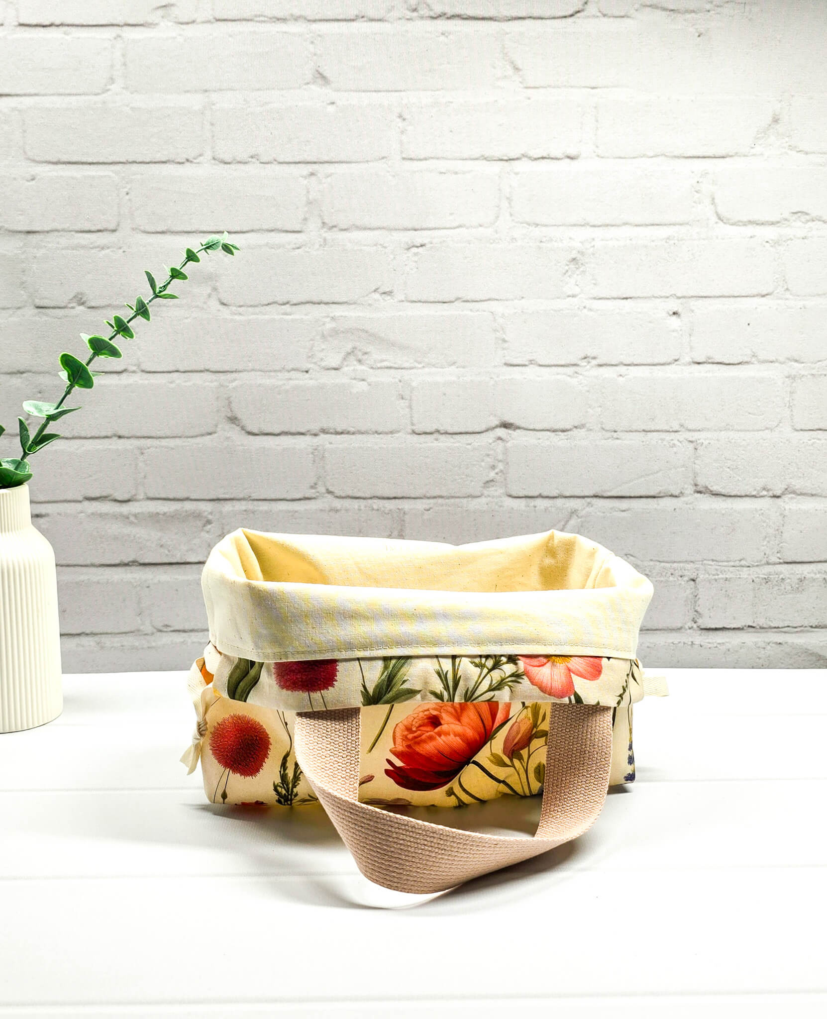 Handgenähte Projekttasche Alva S von Nadelmikado mit feinen botanischen Blumen-Illustrationen auf hellem Stoff, beige Tragehenkel.