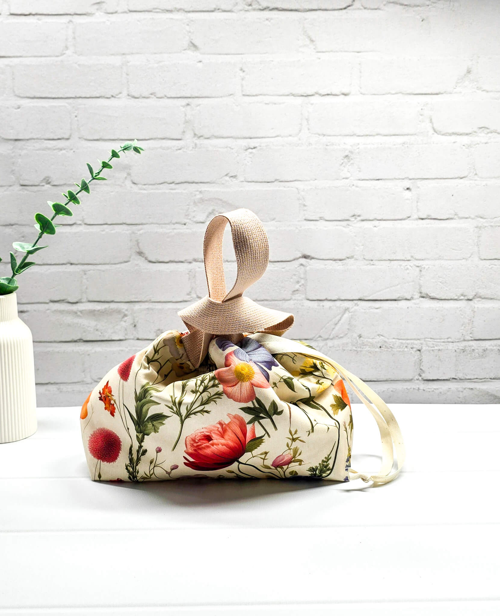 Handgenähte Projekttasche Alva S von Nadelmikado mit feinen botanischen Blumen-Illustrationen auf hellem Stoff, beige Tragehenkel.