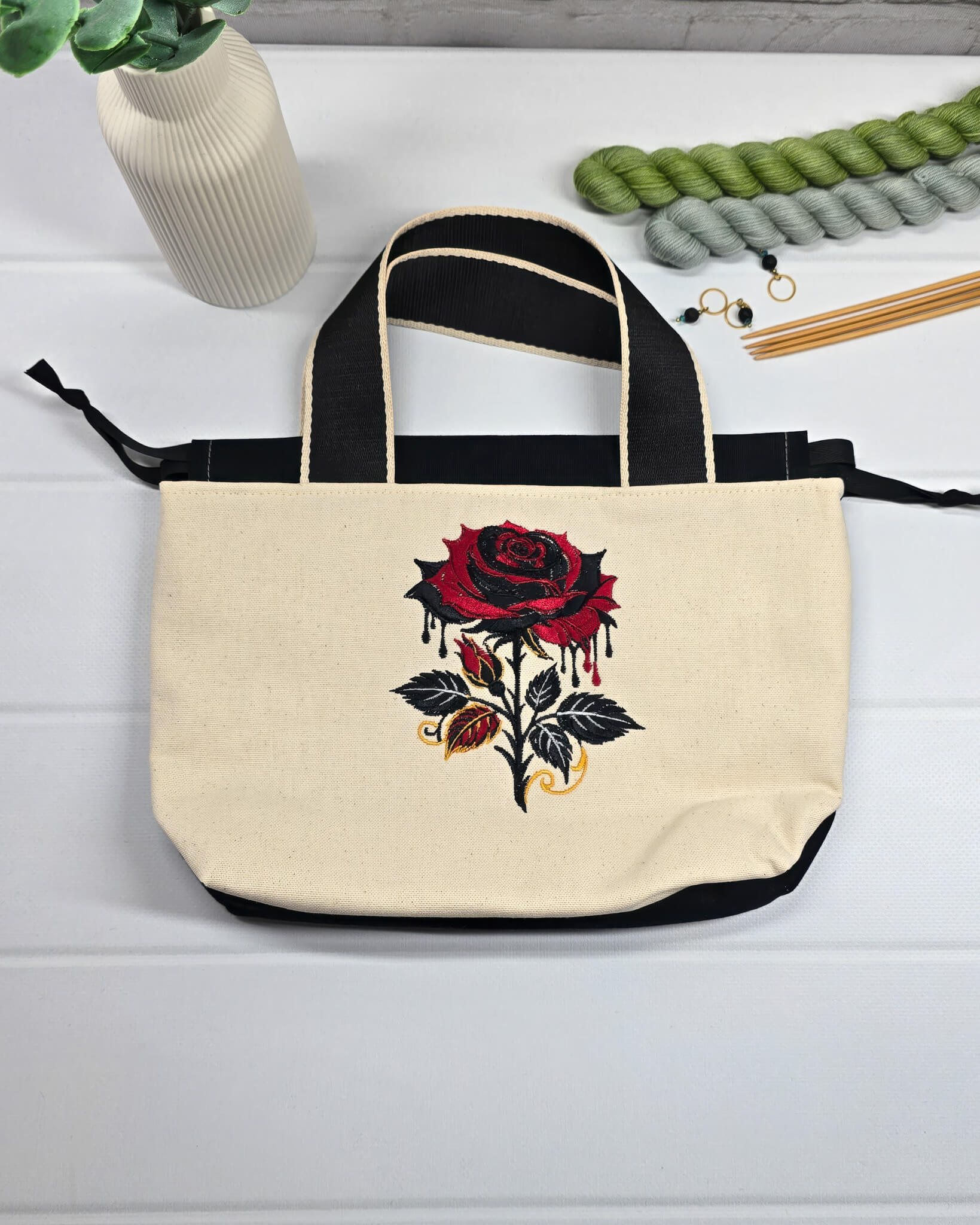 Projekttasche Alva S aus hellem Canvas mit gestickter Gothic Rose, schwarzen Henkeln und Kordelzug. Handgenäht in Bayern von Nadelmikado.