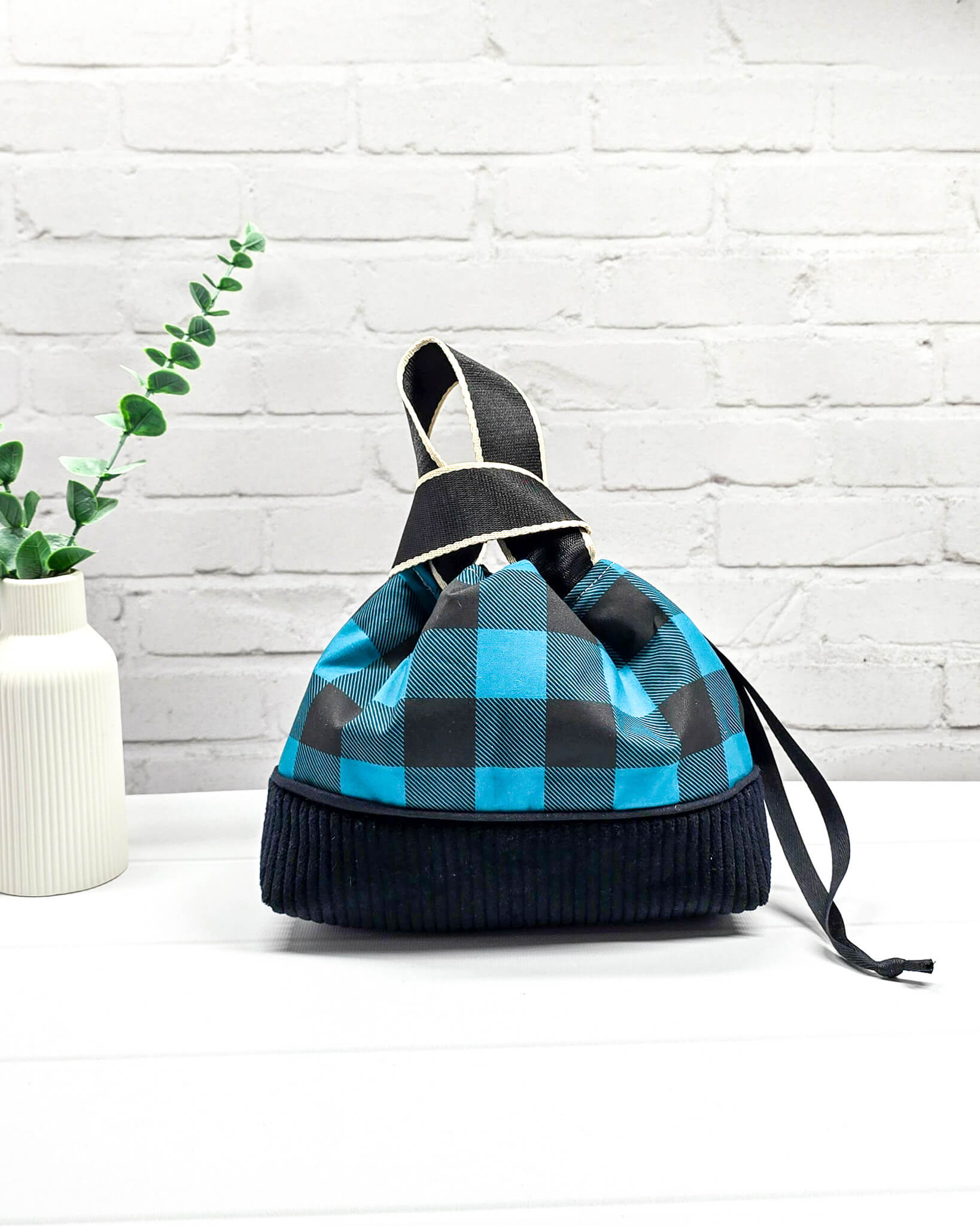 Handgemachte Projekttasche Alva in Größe S mit zwei Tragegriffen, blau-schwarzem Karomuster und einem Taschenboden aus schwarzem Breitcord. Handgenäht in Bayern von Nadelmikado. 