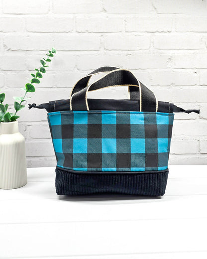 Handgemachte Projekttasche Alva in Größe S mit zwei Tragegriffen, blau-schwarzem Karomuster und einem Taschenboden aus schwarzem Breitcord. Handgenäht in Bayern von Nadelmikado. 