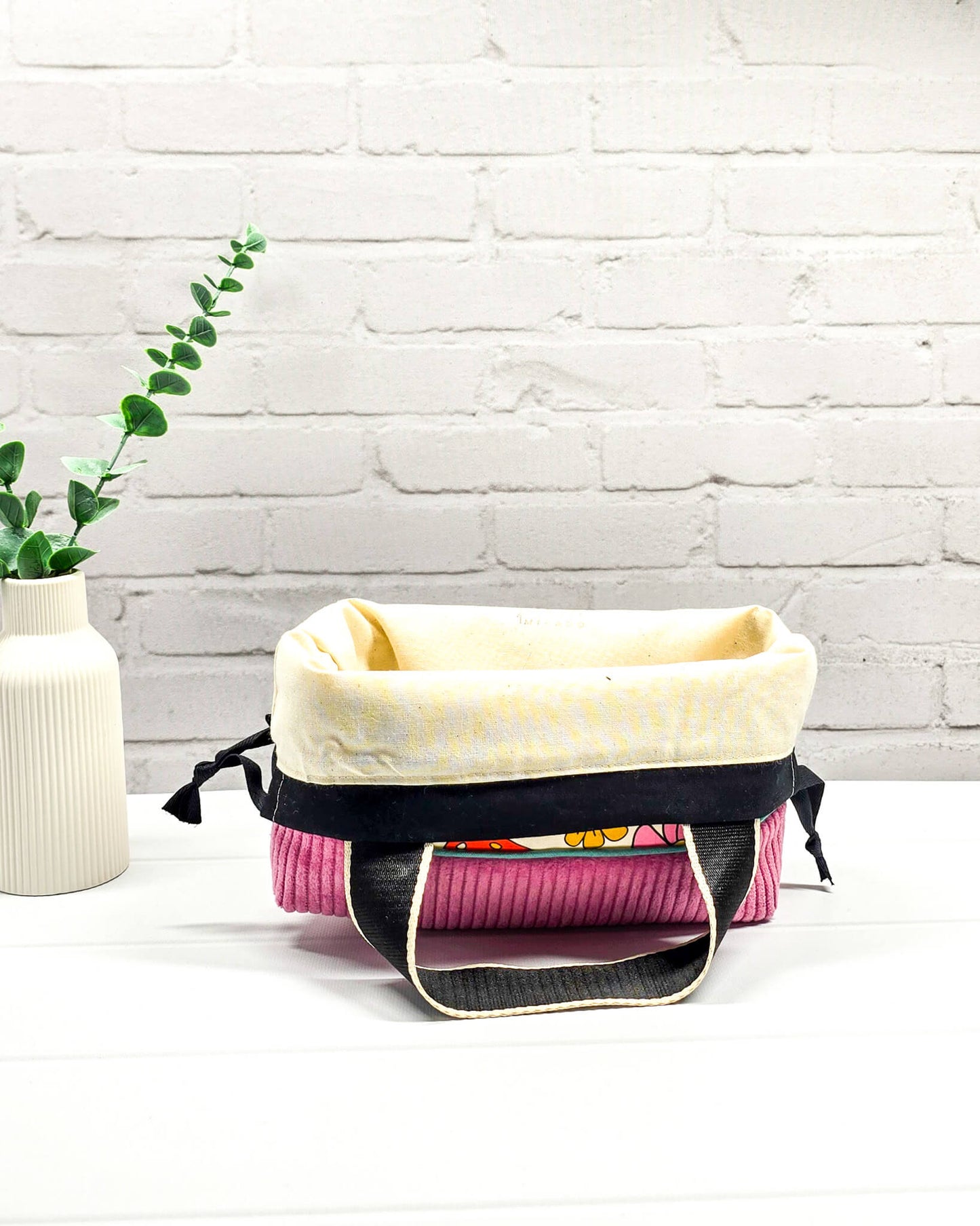 Handgemachte Projekttasche Alva in Größe S mit zwei Tragegriffen, bunten Retro-Pilzen und Blumen auf hellem Stoff und einem Taschenboden aus altrosa Breitcord. Handgenäht in Bayern von Nadelmikado. 