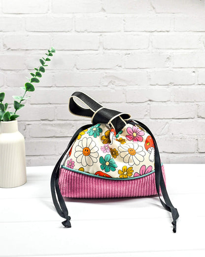 Handgemachte Projekttasche Alva in Größe S mit zwei Tragegriffen, bunten Retro-Pilzen und Blumen auf hellem Stoff und einem Taschenboden aus altrosa Breitcord. Handgenäht in Bayern von Nadelmikado. 