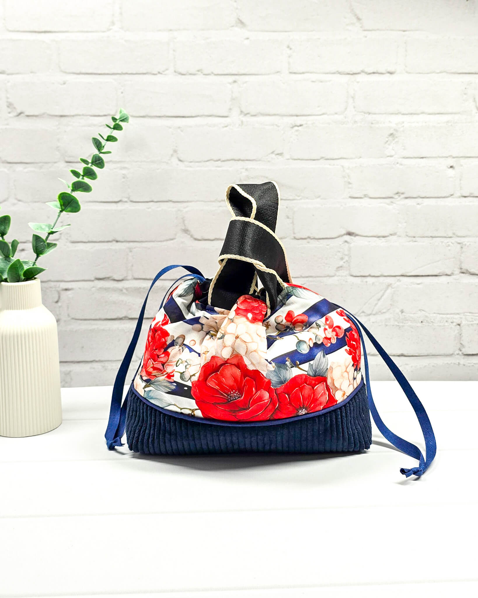 Projekttasche Alva in Größe S mit zwei Tragegriffen, roten Rosen auf blau-weiß gestreiftem Stoff und einem Taschenboden aus dunkelblauem Breitcord. Handgenäht in Bayern von Nadelmikado. 